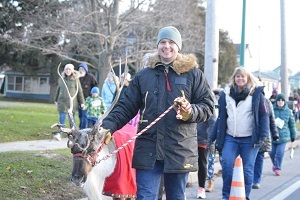 A reindeer being led at the front of a group of people.