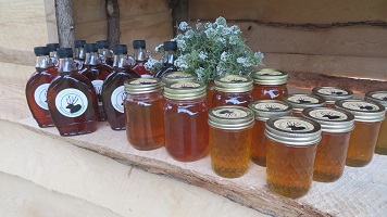 Bottles of maple syrup and jars of honey with the farm logo on them sit very prettily on a wood shelf.